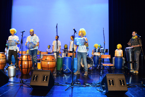 Jóvenes tocando percusión con botellas plásticas y tarros.