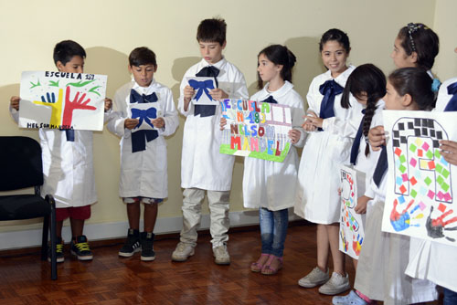 Niños de escuela pública recitando frases de Mandela y sosteniendo dibujos alusivos.